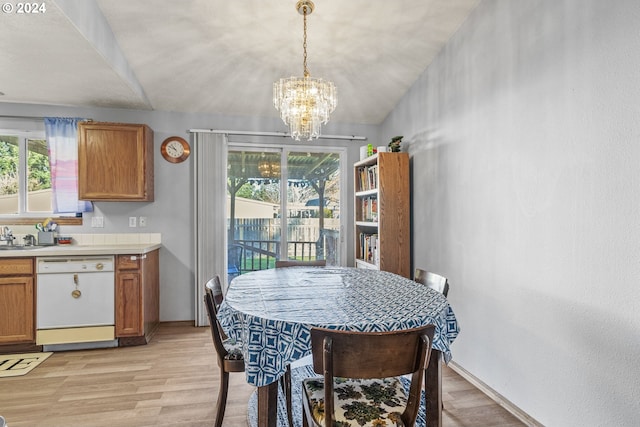 dining area featuring vaulted ceiling, light hardwood / wood-style flooring, plenty of natural light, and a notable chandelier