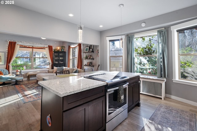 kitchen featuring a wealth of natural light, decorative light fixtures, stainless steel range with electric cooktop, dark brown cabinets, and light hardwood / wood-style flooring