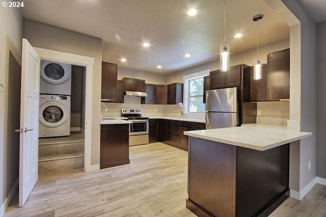 kitchen featuring appliances with stainless steel finishes, dark brown cabinets, stacked washer / drying machine, decorative light fixtures, and kitchen peninsula