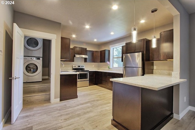 215 NE 30th Ave, Portland, OR 97232 - kitchen with appliances with stainless steel finishes, stacked washer and clothes dryer, under cabinet range hood, dark brown cabinetry, and a peninsula