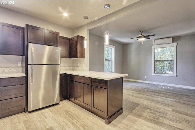 215 NE 30th Ave, Portland, OR 97232 - kitchen with freestanding refrigerator, light wood-type flooring, a peninsula, a wall mounted air conditioner, and dark brown cabinets