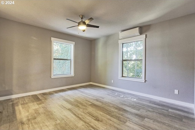 unfurnished room featuring light hardwood / wood-style flooring, a wall unit AC, and ceiling fan