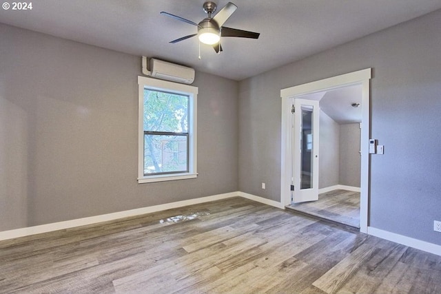 empty room featuring wood-type flooring, ceiling fan, and a wall unit AC