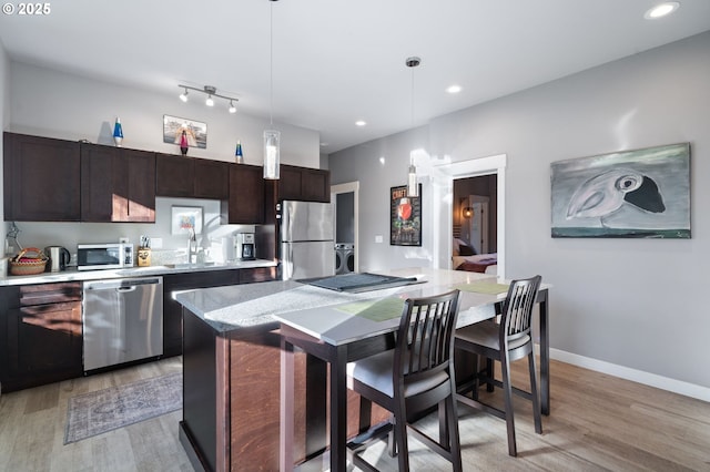 kitchen featuring decorative light fixtures, a center island, dark brown cabinets, light hardwood / wood-style flooring, and stainless steel appliances