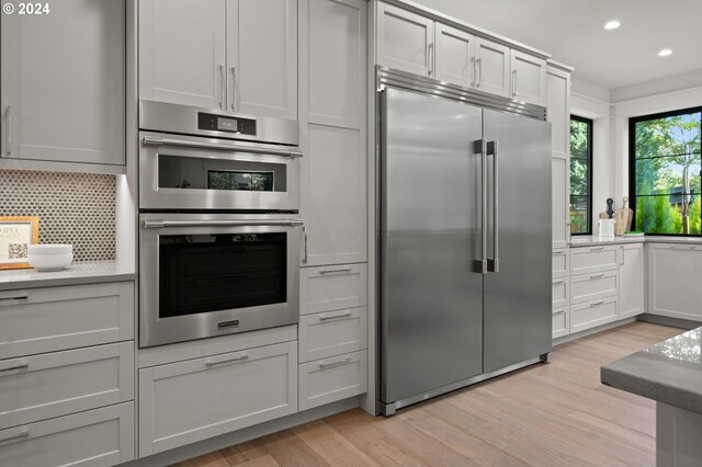 kitchen with light hardwood / wood-style flooring, stainless steel appliances, and backsplash