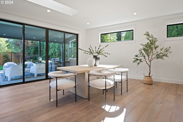 dining room featuring light wood-type flooring and a skylight