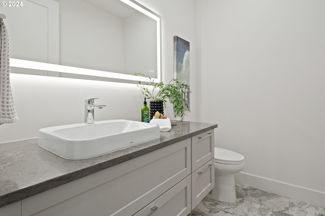 bathroom featuring marble finish floor, baseboards, vanity, and toilet