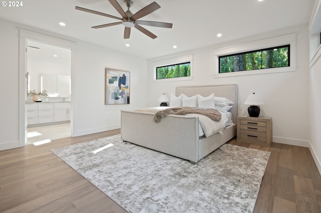 bedroom with recessed lighting, ensuite bath, baseboards, and wood finished floors