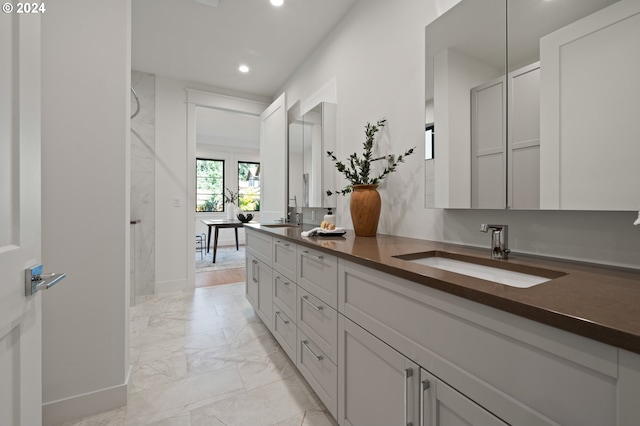 interior space featuring marble finish floor, double vanity, a sink, and recessed lighting