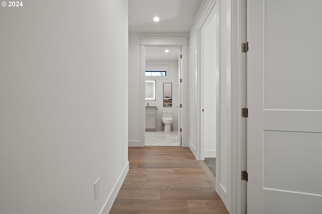 hall featuring light wood finished floors, recessed lighting, and baseboards