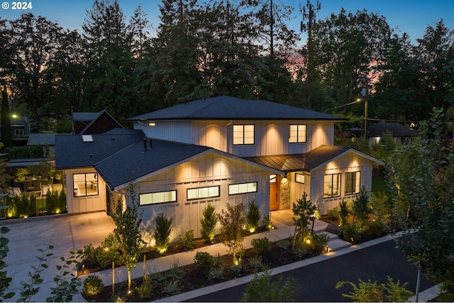 view of front of property featuring board and batten siding, a standing seam roof, driveway, and metal roof