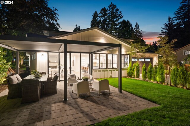 patio terrace at dusk with an outdoor living space and a yard