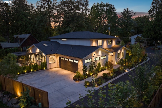 view of front of house with a garage, stone siding, fence, and driveway