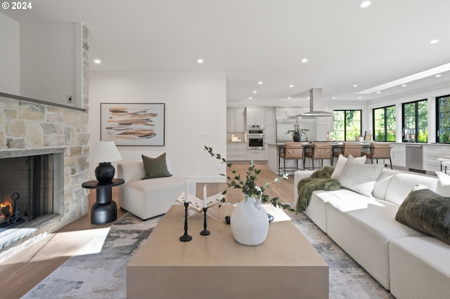 living room with recessed lighting, light wood-style flooring, and a stone fireplace