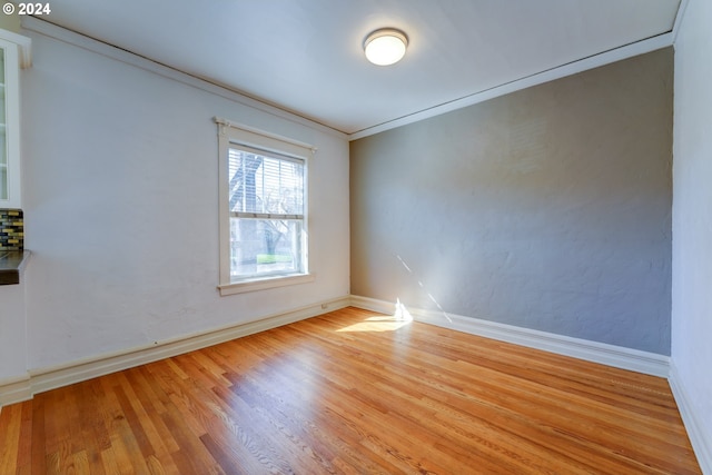 unfurnished room featuring ornamental molding and light wood-type flooring