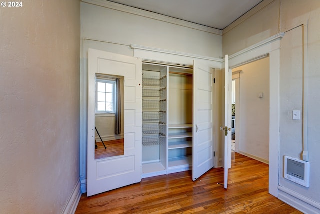 unfurnished bedroom with crown molding, a closet, and dark wood-type flooring