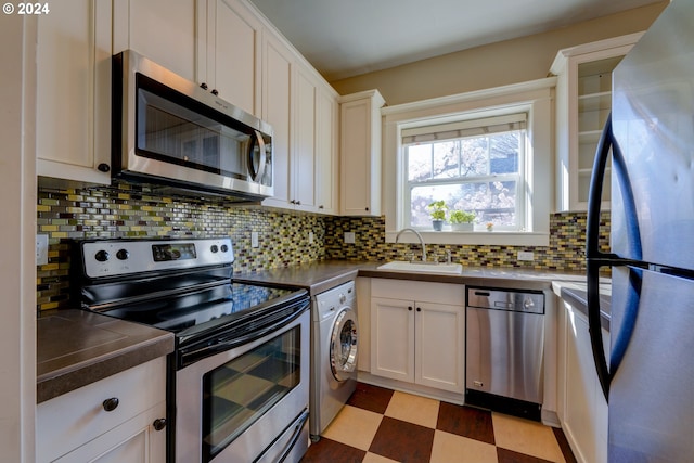 kitchen featuring sink, white cabinets, backsplash, stainless steel appliances, and washer / clothes dryer