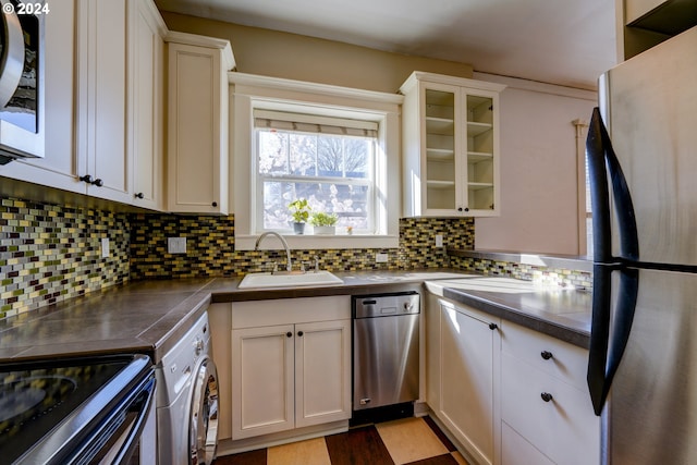 kitchen featuring washer / dryer, appliances with stainless steel finishes, tasteful backsplash, white cabinetry, and sink