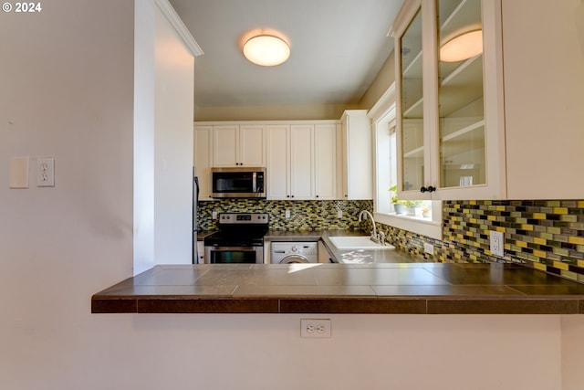 kitchen featuring stainless steel appliances, backsplash, sink, washer / clothes dryer, and white cabinets