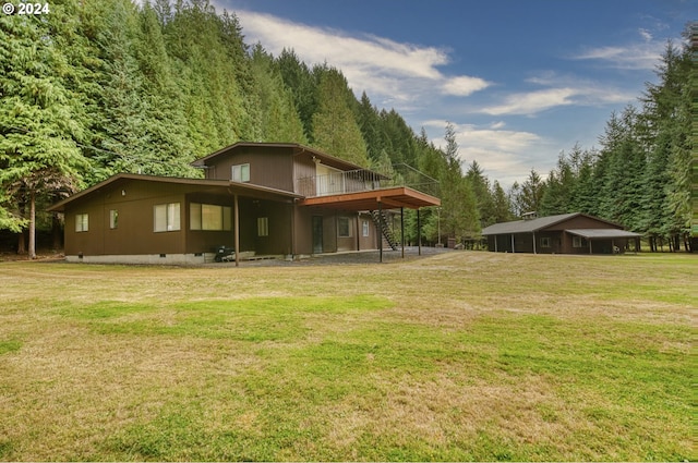 back of property featuring a balcony and a lawn