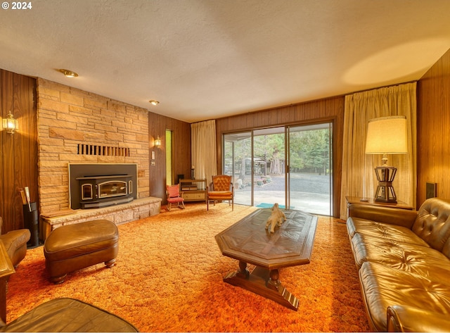 living room with wood walls, carpet flooring, and a stone fireplace