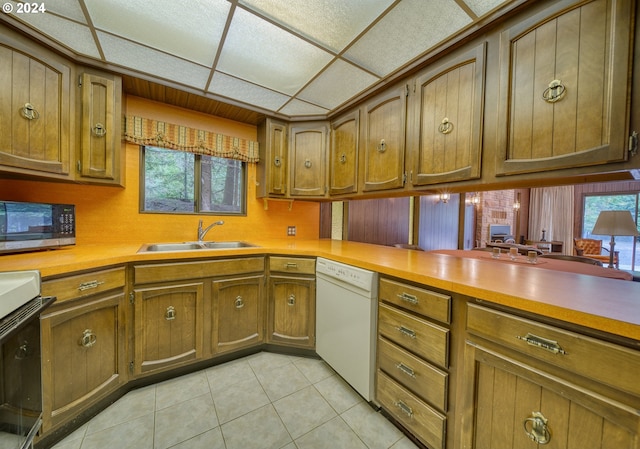 kitchen with light tile floors, sink, white dishwasher, and a wealth of natural light