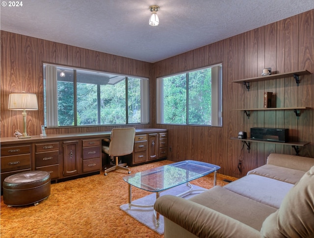 carpeted living room featuring wooden walls and a textured ceiling