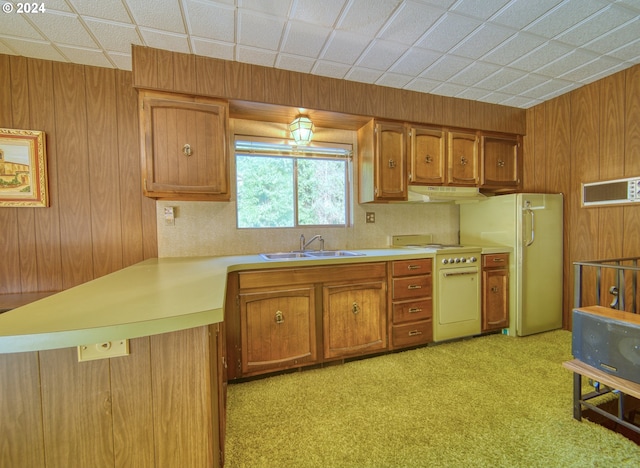 kitchen featuring kitchen peninsula, hanging light fixtures, white appliances, sink, and light carpet