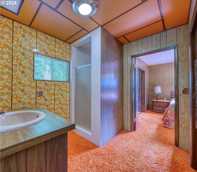 bathroom with wood walls, an enclosed shower, and sink