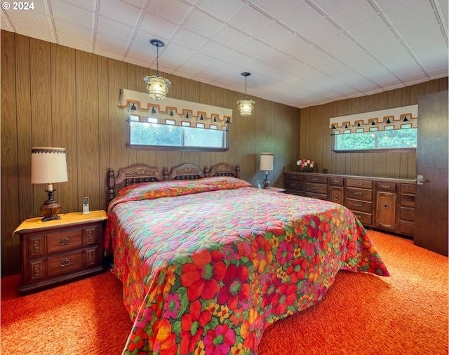 bedroom with an inviting chandelier, carpet flooring, and wooden walls