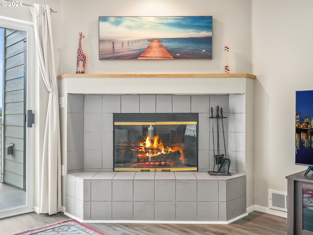 room details with hardwood / wood-style floors and a tiled fireplace