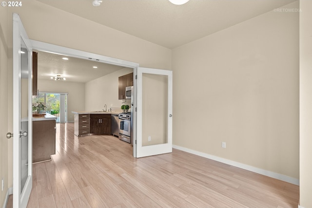 spare room featuring a textured ceiling, light wood-type flooring, sink, and french doors