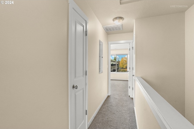 corridor featuring light colored carpet and a textured ceiling