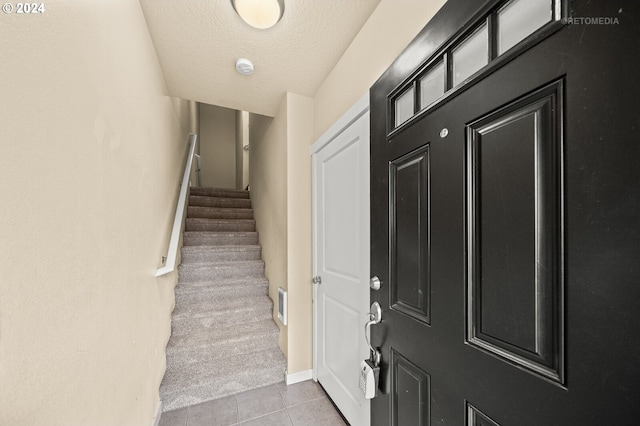 entryway with light tile patterned floors and a textured ceiling