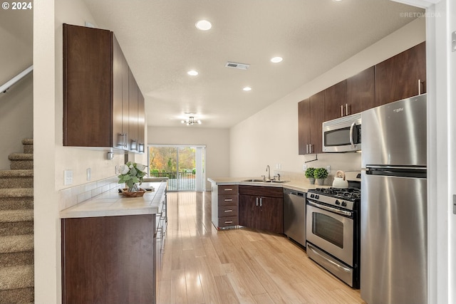 kitchen with dark brown cabinetry, sink, light hardwood / wood-style floors, and appliances with stainless steel finishes