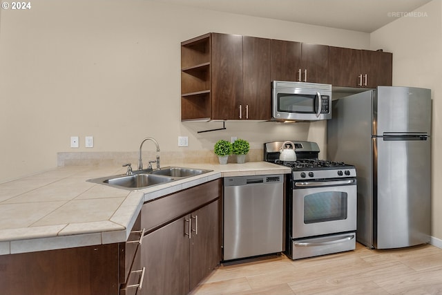 kitchen with tile countertops, sink, dark brown cabinets, and appliances with stainless steel finishes