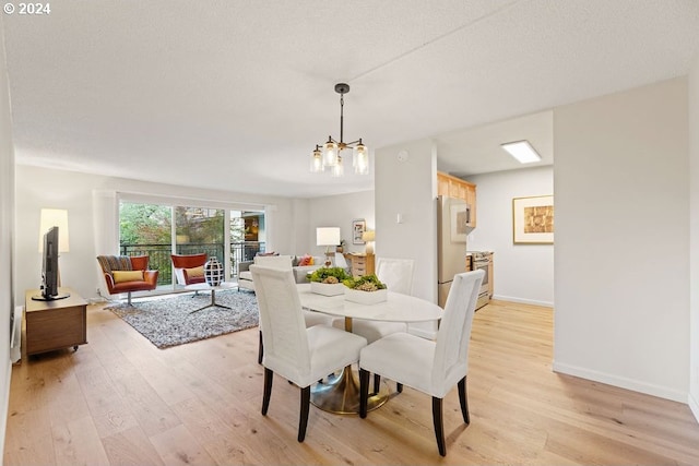 dining area with a chandelier, light hardwood / wood-style floors, and a textured ceiling