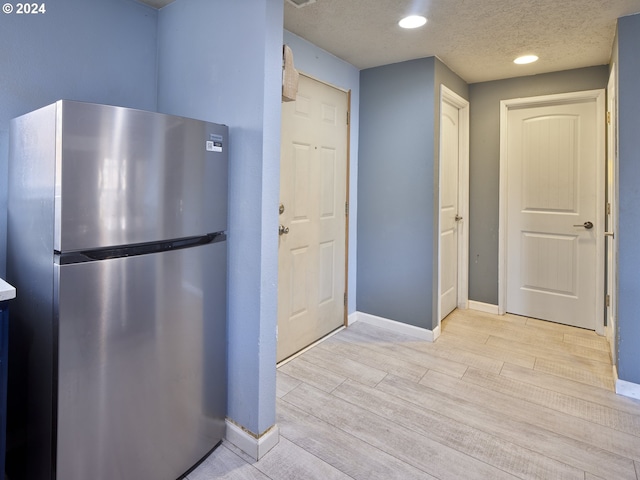 kitchen featuring a textured ceiling, stainless steel fridge, and light hardwood / wood-style floors