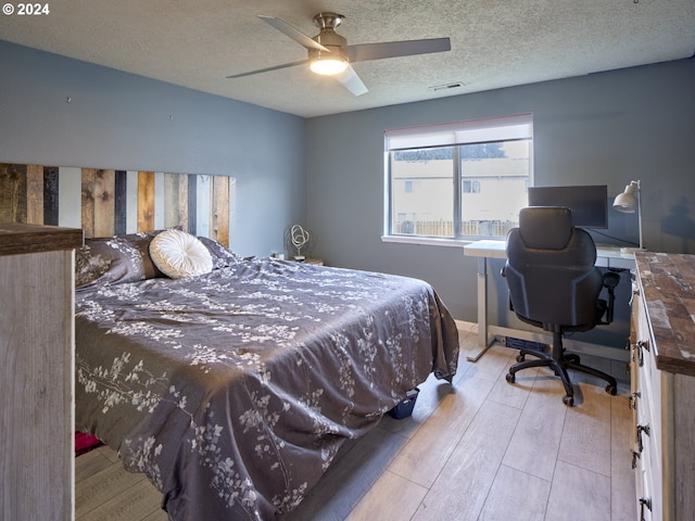 bedroom featuring ceiling fan, a textured ceiling, and light wood-type flooring