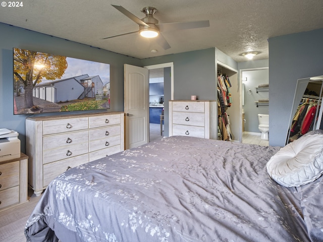 bedroom featuring ceiling fan, ensuite bathroom, a textured ceiling, a spacious closet, and a closet