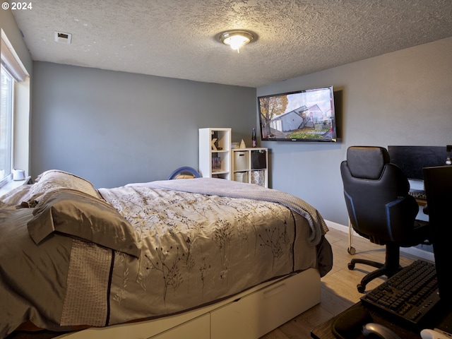 bedroom with a textured ceiling and light hardwood / wood-style flooring