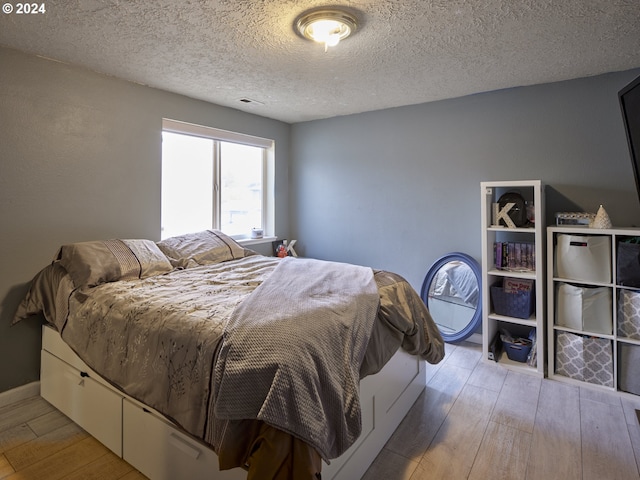 bedroom featuring hardwood / wood-style flooring and a textured ceiling