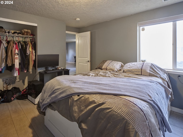 bedroom with light hardwood / wood-style flooring, a closet, and a textured ceiling