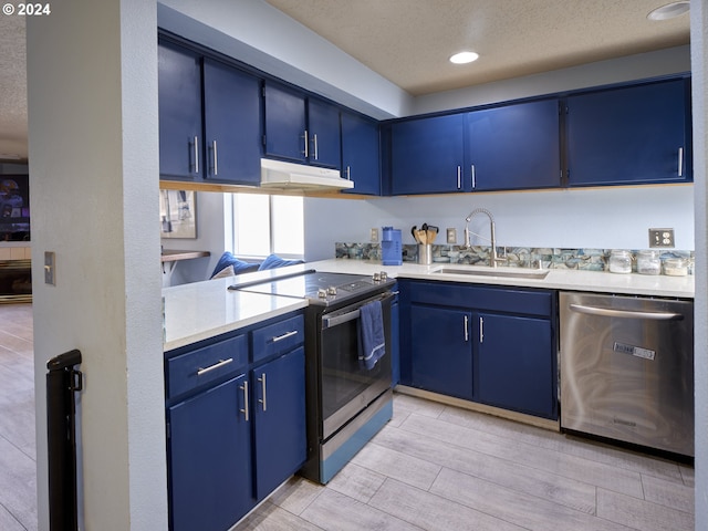 kitchen featuring appliances with stainless steel finishes, blue cabinetry, sink, and a textured ceiling