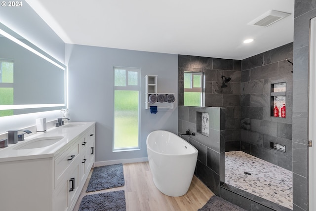 bathroom with plus walk in shower, plenty of natural light, wood-type flooring, and vanity