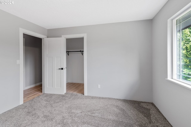 unfurnished bedroom with carpet floors, a closet, and a spacious closet