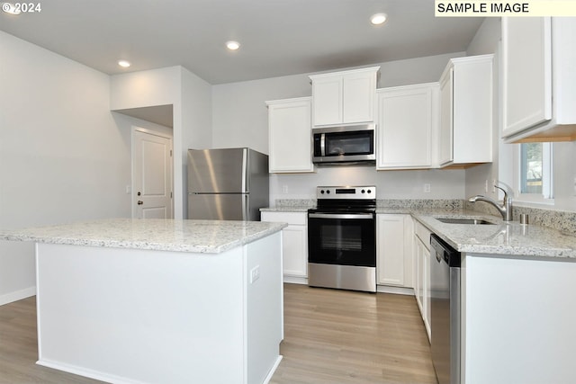 kitchen featuring white cabinets, light wood-type flooring, appliances with stainless steel finishes, sink, and a kitchen island