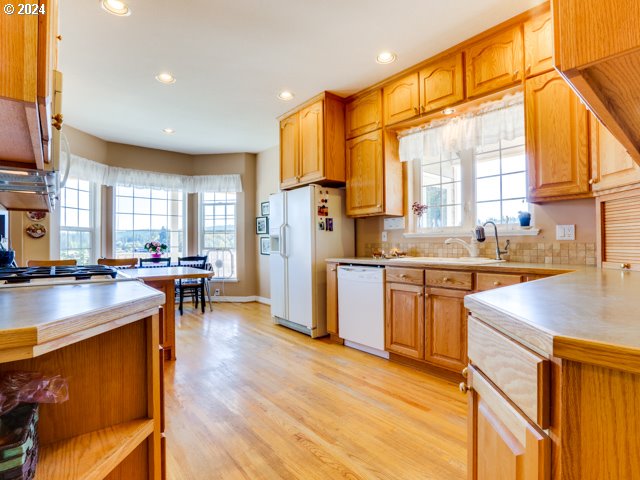 kitchen with white appliances, light hardwood / wood-style floors, sink, decorative backsplash, and kitchen peninsula