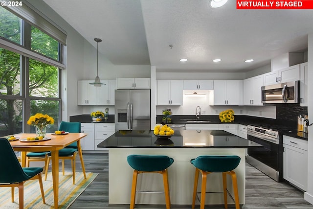 kitchen with sink, a center island, white cabinets, decorative light fixtures, and appliances with stainless steel finishes