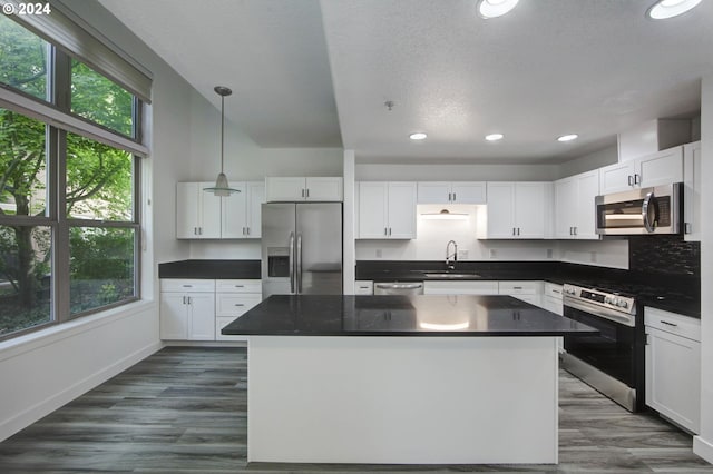 kitchen with appliances with stainless steel finishes, a center island, plenty of natural light, and white cabinets